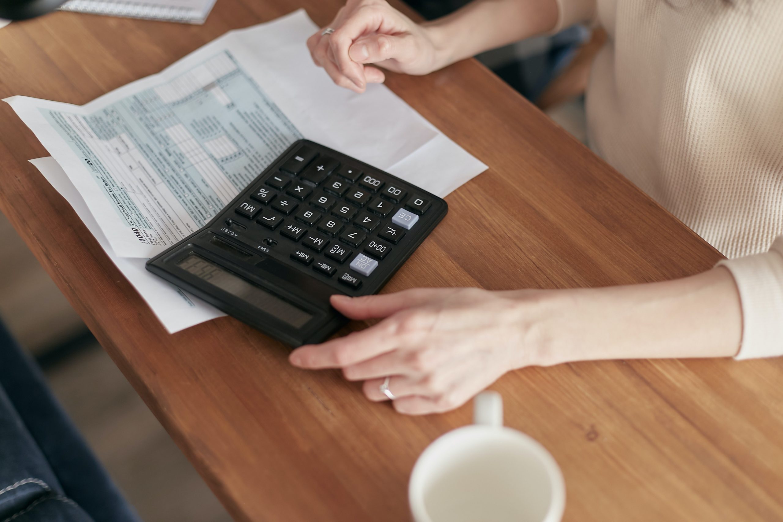 a woman calculates the cost of TMS therapy using a calculator and paper bills.