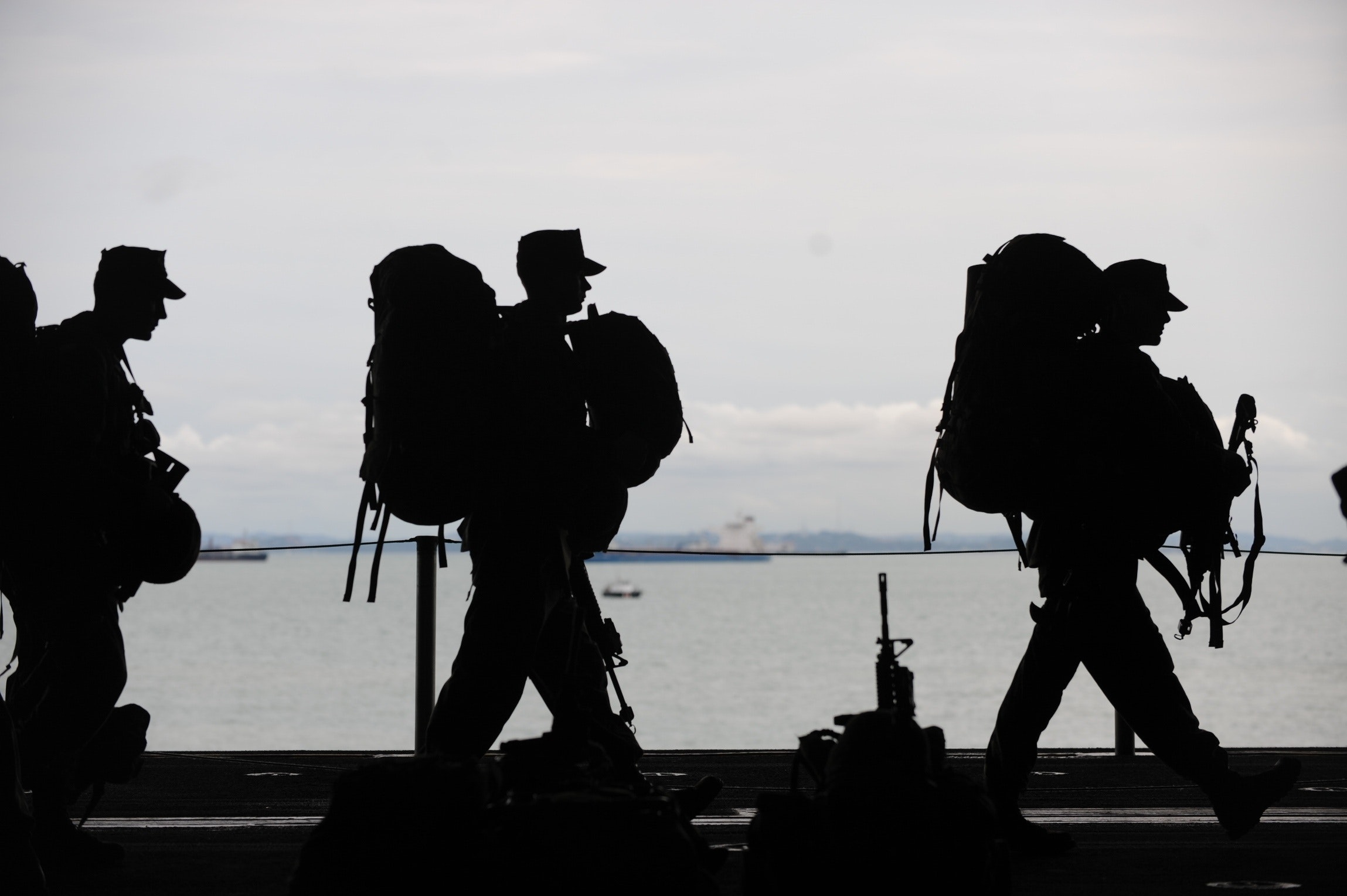 three veterans in shadow walk across a scene of water. Veterans are at risk for specific mental health problems because of their time serving.